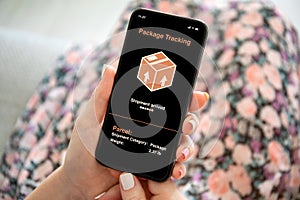 Female hands holding phone with app tracking delivery package