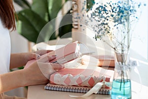 Female hands holding pink coral coloured leather diary 2021 while sitting near a window at cafe
