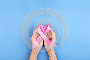 female hands holding a pink ribbon for breast cancer awareness, concept medicine, concept research