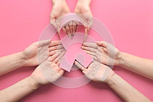 Female hands holding pink ribbon on color background. Breast cancer awareness concept