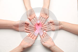 Female hands holding pink ribbon on white background. Breast cancer awareness concept