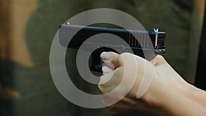 Female hands holding pistol ready shoots to target, close-up