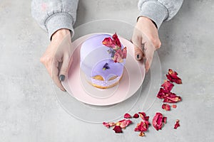 Female hands holding plate with lavender easter cake with modern decoration of ribbons and flowers