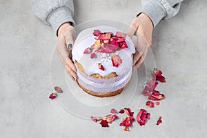 Female hands holding plate with lavender easter cake with modern decoration of ribbons and flowers