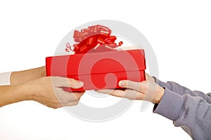 Female hands holding red gift box with red ribbon giving presetn to somebody on grey background. Present for birthday, valentine