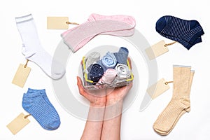 Female hands holding shopping basket with socks among women`s cotton socks set with price tags on white background. Fashionable