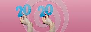 Female hands holding and showing date 2020 cut out of cardboard on a colored pink background, concept new year,creative idea