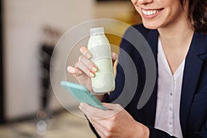 Female hands holding a small bottle and a smartphone