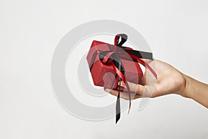 Female hands holding small gift box with ribbon on white background
