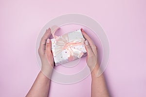 Female Hands Holding a Small Present Box Pink Background Top View Gifft Concept