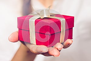 Female hands holding a small red box with a gift. Birthday concept