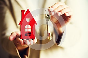 Female hands holding small red house and keys. Real estate agent offer you house or apartment. Property insurance and