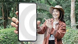 Female hands holding a smartphone with mock up. Young woman holding big smartphone with blank white screen at forest park Road
