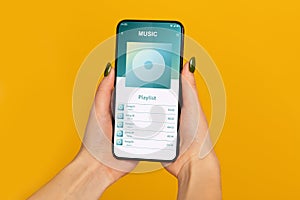 Female Hands Holding Smartphone With Opened Music Player Playlist On Screen