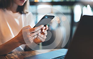 Female hands holding smartphone using laptop office, hipster girl freelancer writing on mobile phone, businesswoman working