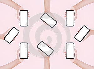 Female hands holding smartphones with mockup on background of pastel pink color.