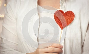 Female hands holding sparkling red heart near body, taking care, Health, Valentine& x27;s Day concept romantic design