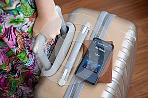 Female hands holding suitcase phone with airplane ticket application airlines