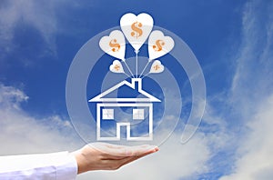 Female hands holding symbol of house with balloon and symbol of dollar on blue sky background, Save money for prepare in future