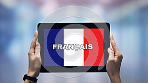 Female hands holding tablet with French word against national flag, online app