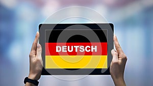 Female hands holding tablet with German word against national flag, online app