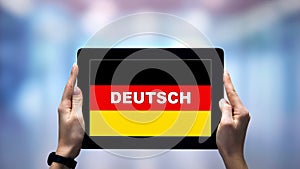 Female hands holding tablet with German word against national flag, online app