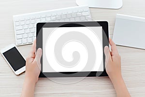 female hands holding a tablet with a isolated screen over a table