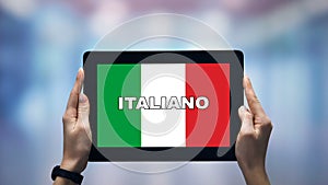 Female hands holding tablet with Italian word against national flag, online app