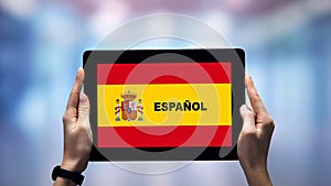 Female hands holding tablet with Spanish word against national flag, online app