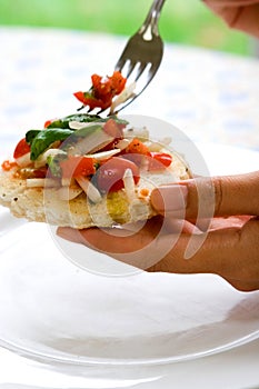 Female hands holding tomato salad on toasted bread