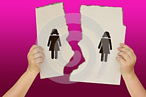 Female hands holding a torn poster separating the symbols of two women, the concept of severing same-sex relations, divorce,
