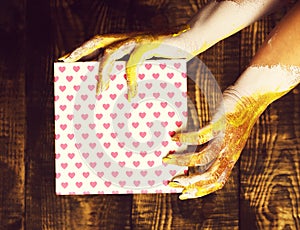 Female hands holding valentine present on brown vintage studio background