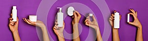 Female hands holding white cosmetics bottles - lotion, cream, serum on violet background. Banner. Skin care, pure beauty, body