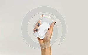 Female hands holding white deodorant. Isolated on gray background. Closeup