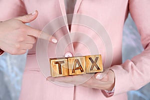 Female hands holding wooden blocks with word TAX