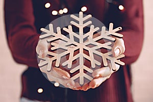 Female hands holding wooden snowflake, christmas decoration