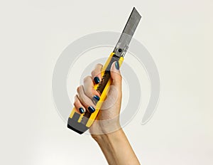 Female hands holding yellow sharp box cutter. on gray b