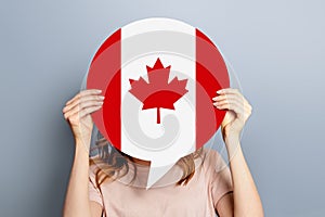 female hands holds blank white speech bubble with canadian flag  on grey background
