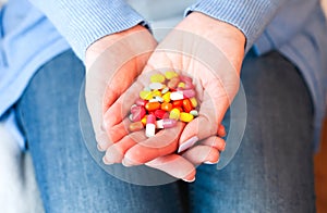 Female hands holds many multicolored pills. Taking vitamins, supplements, antibiotic, antidepressant and painkiller medication.