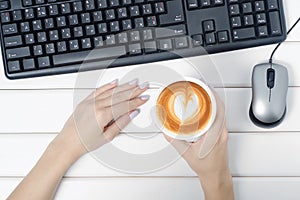 Female hands keyboard mouse from computer cup of coffee