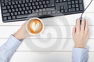 Female hands keyboard mouse from computer cup of coffee