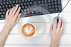 Female hands keyboard mouse from computer cup of coffee