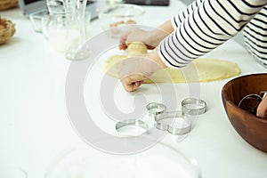 Female hands knead the dough on white table , beautiful directional lighting. Concept of home baking and comfort