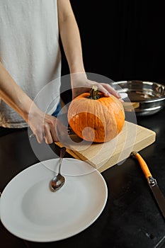 Female hands with knife chopping pumpkin on cutting board. Preparing autumn vegetables.