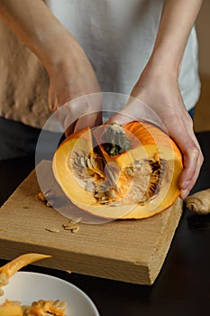 Female hands with knife chopping pumpkin on cutting board. Preparing autumn vegetables. Healthy organic vegetarian food