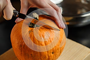 Female hands with knife chopping pumpkin on cutting board. Preparing autumn vegetables. Healthy organic vegetarian food