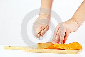 Female hands with a knife chops carrot on a cutting board