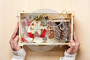 Female hands laid care package, seasonal gift box with coffee, gingerbread and cinnamon Personalized eco friendly basket for