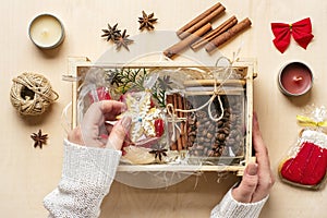 female hands laid care package, seasonal gift box with coffee, gingerbread and cinnamon Personalized eco friendly basket for