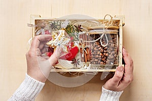 female hands laid care package, seasonal gift box with coffee, gingerbread and cinnamon Personalized eco friendly basket for